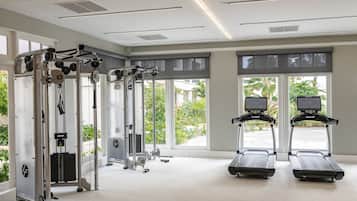 Un gimnasio con equipo de cardio, máquinas de pesas y amplias ventanas que dan a zonas verdes.