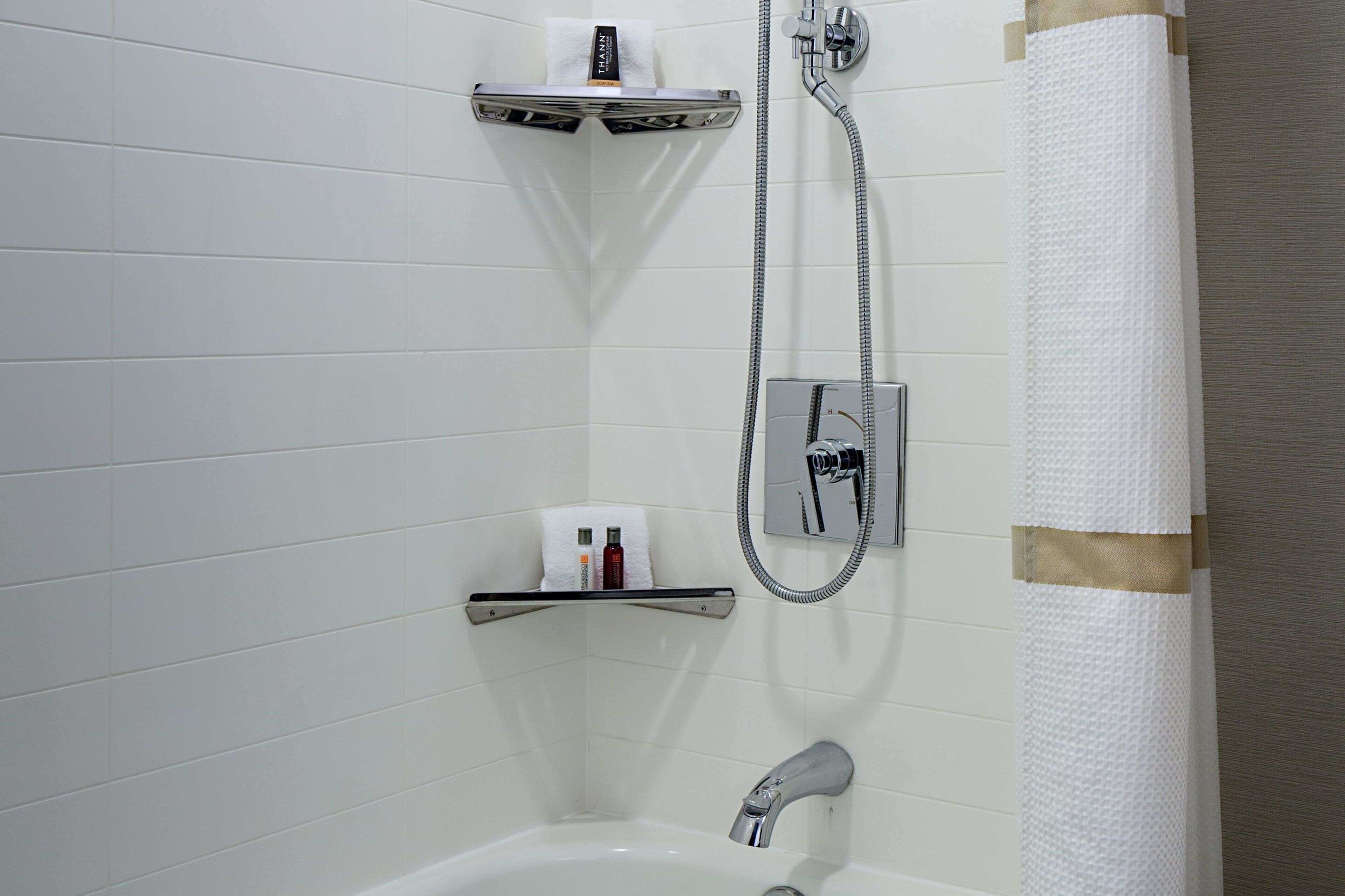 A bathroom with a shower, a toilet paper holder, and a towel rack.
