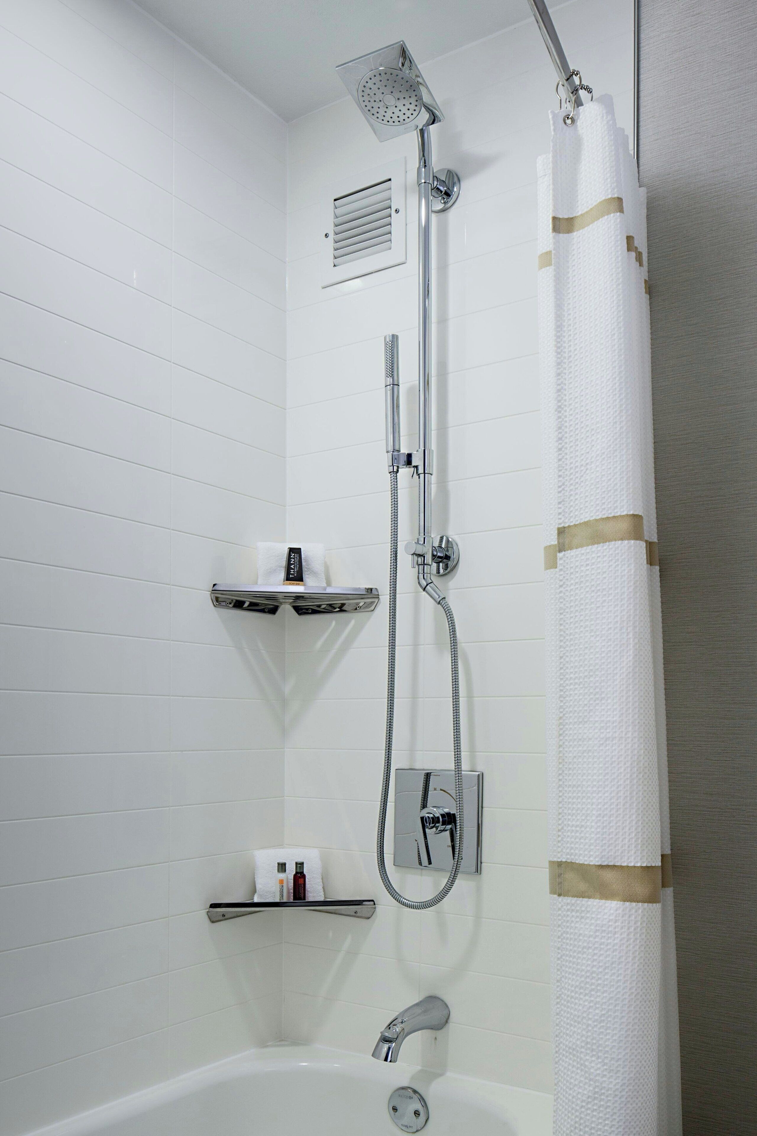 Een moderne badkamer met een douche, een bad en een toiletpapierhouder.