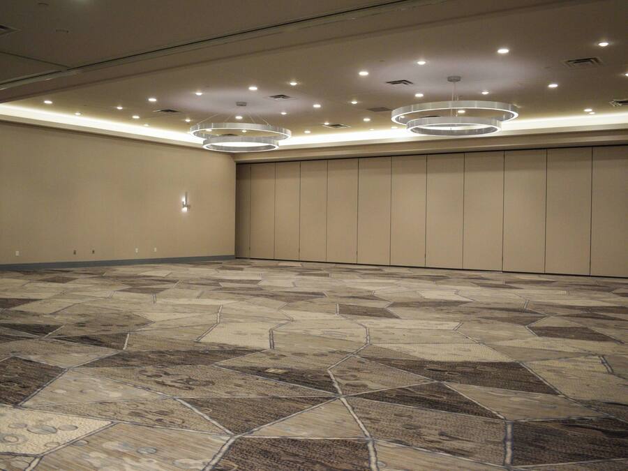 A spacious room with a patterned floor, recessed lighting, and a large wall with vertical panels.