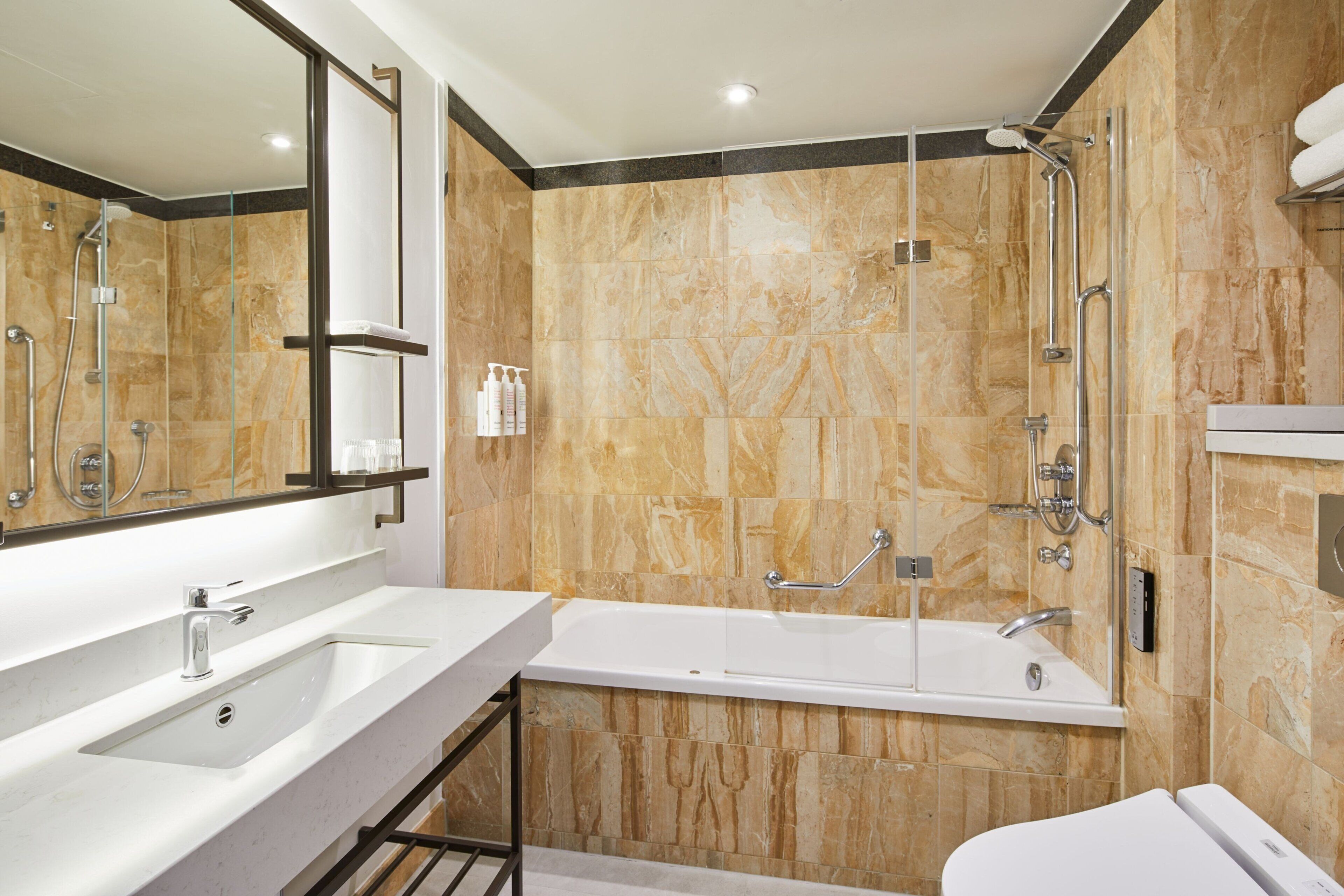 A modern bathroom with a large mirror, two sinks, a bathtub, and a shower.