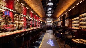 Un bar doté d’un long comptoir, de plusieurs espaces pour s’asseoir et d’un sol à motifs.