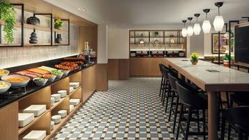 A modern kitchen with a checkered floor, wooden shelves, and a long counter with food items.