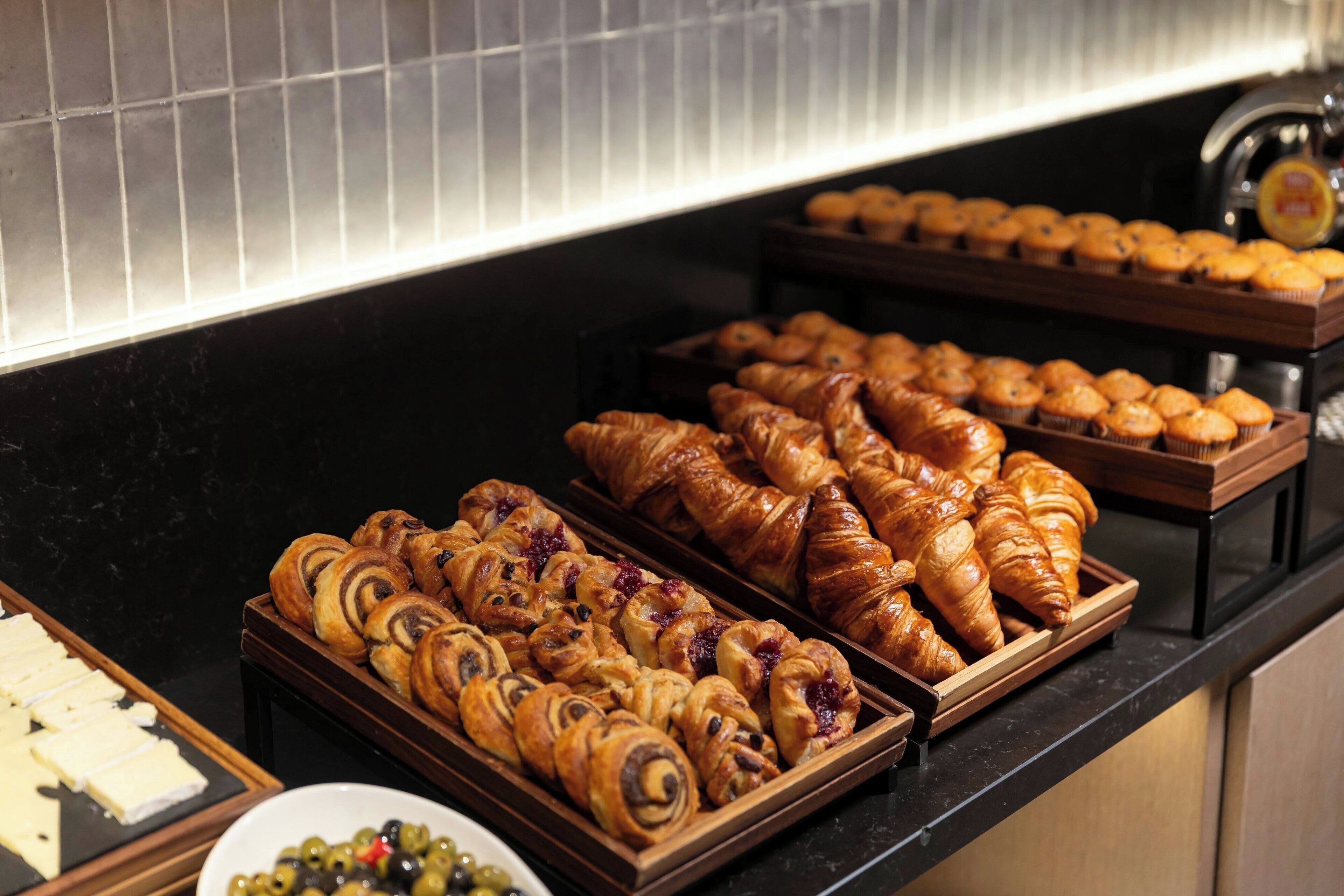 A buffet with various pastries and cheeses.