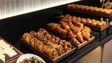 A buffet with various pastries and cheeses.