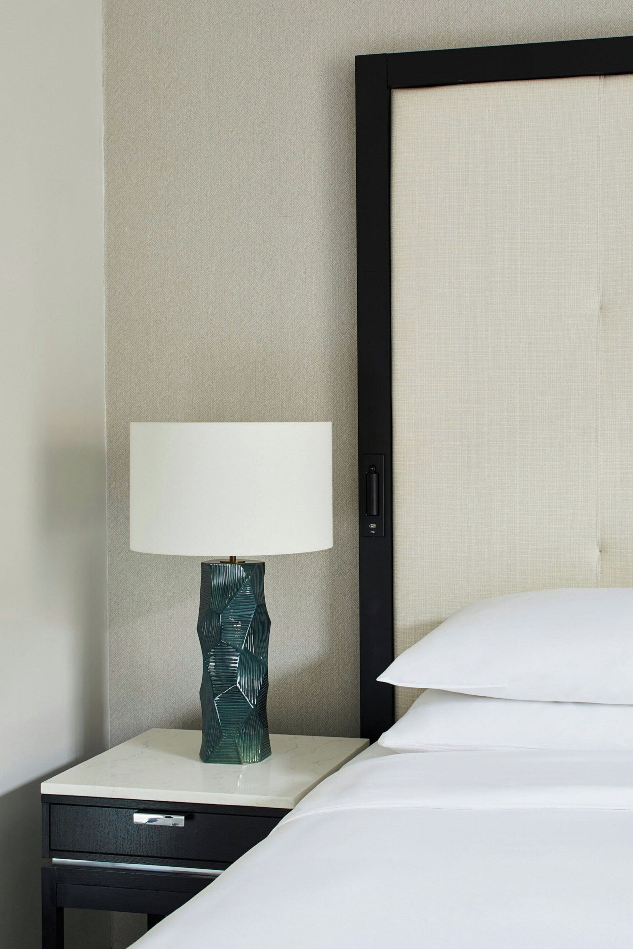 Une chambre d’hôtel avec un lit, une table de chevet avec une lampe et un panneau mural.