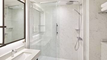 A modern bathroom with a glass-enclosed shower, a white sink, and a large mirror.