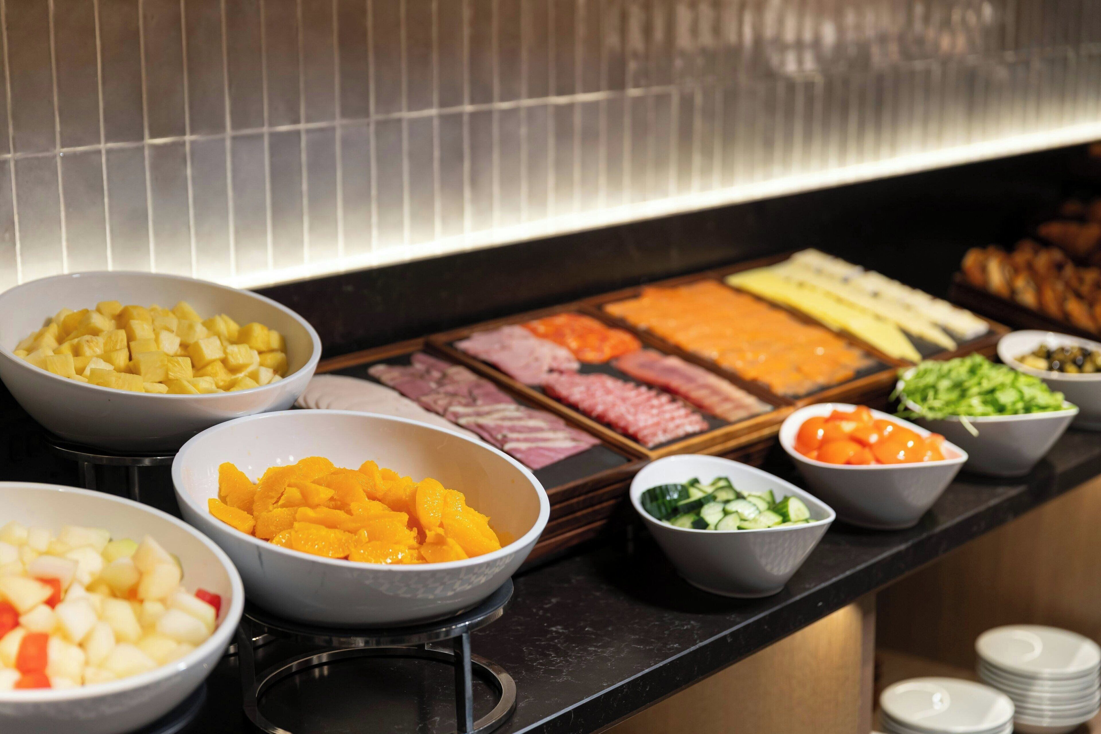 A buffet with various food items including fruits, meats, and salads.