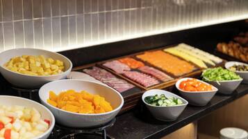 A buffet with various food items including fruits, meats, and salads.