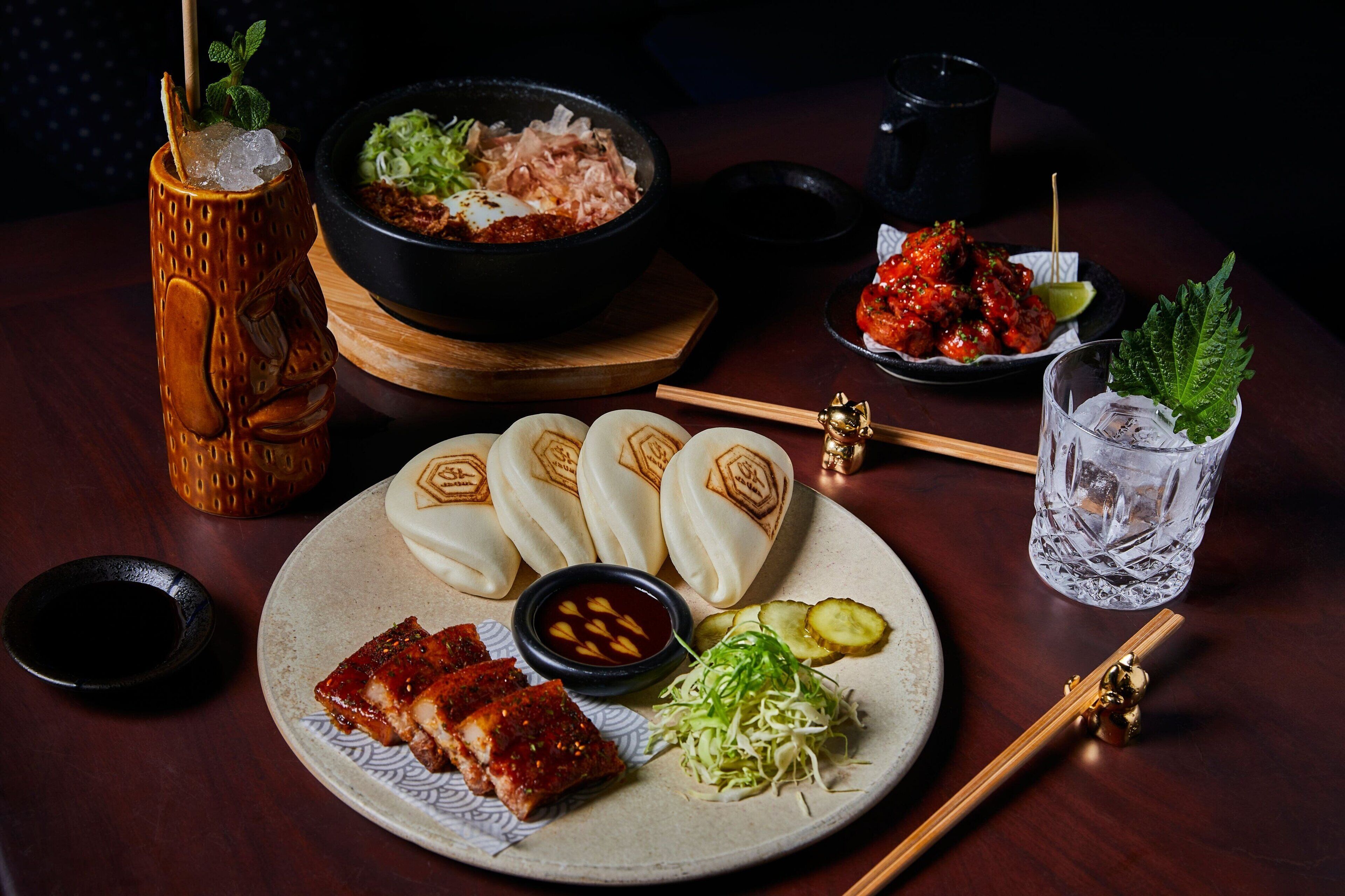 A table with various dishes including dumplings, ribs, and a bowl of soup.