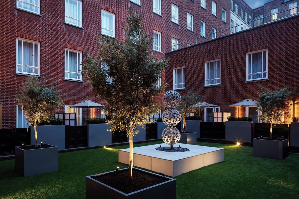 A courtyard with a brick building, planters, and a spherical sculpture.