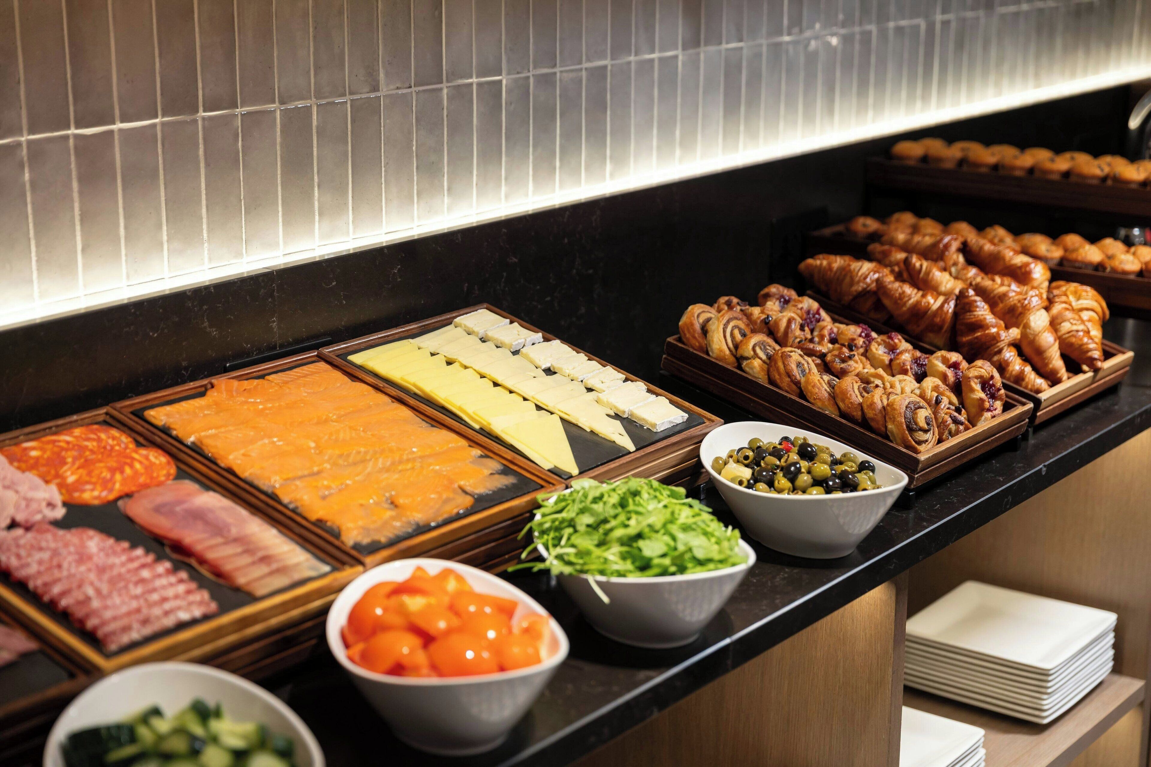 A buffet with various food items including meats, cheeses, and pastries.