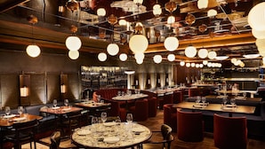 Un restaurant doté de nombreuses tables, de banquettes rouges rembourrées et de luminaires sphériques suspendus au plafond.