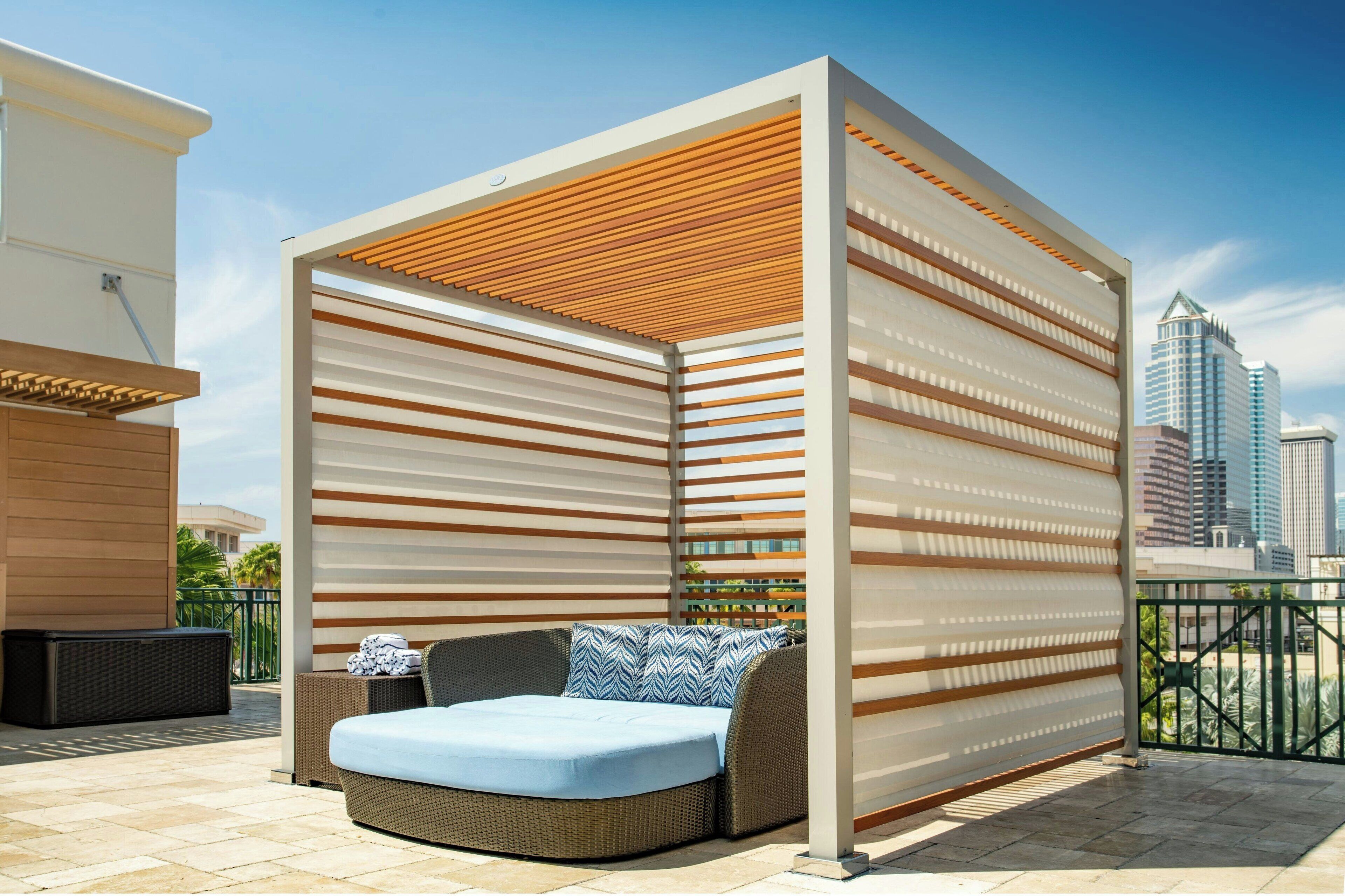 A modern outdoor seating area with a cushioned bench and a wooden slatted partition.