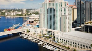 Un hotel moderno de gran altura con un puerto deportivo lleno de barcos, un puente y otros edificios al fondo.