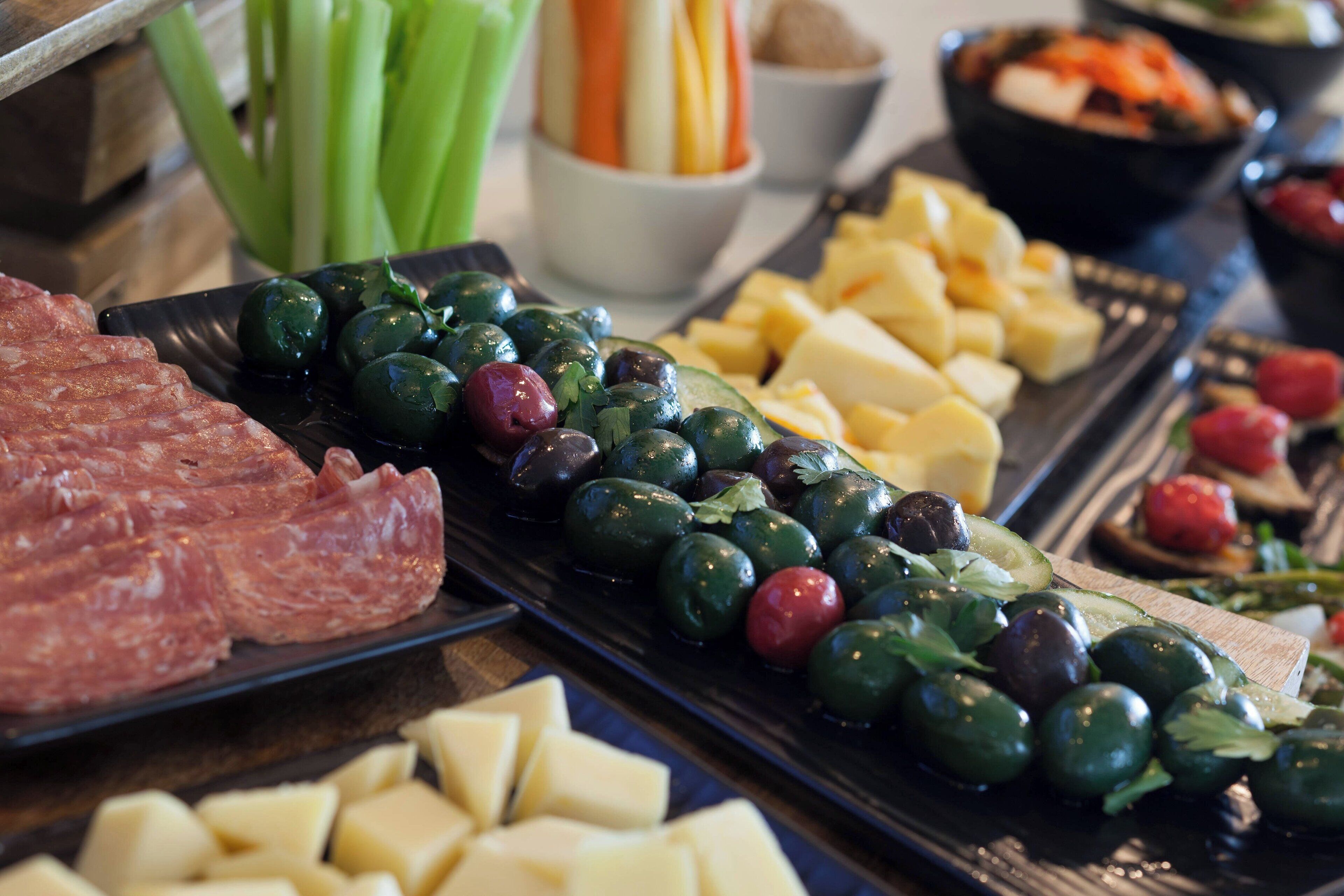 A variety of food items including cheese, olives, and meat on a serving tray.