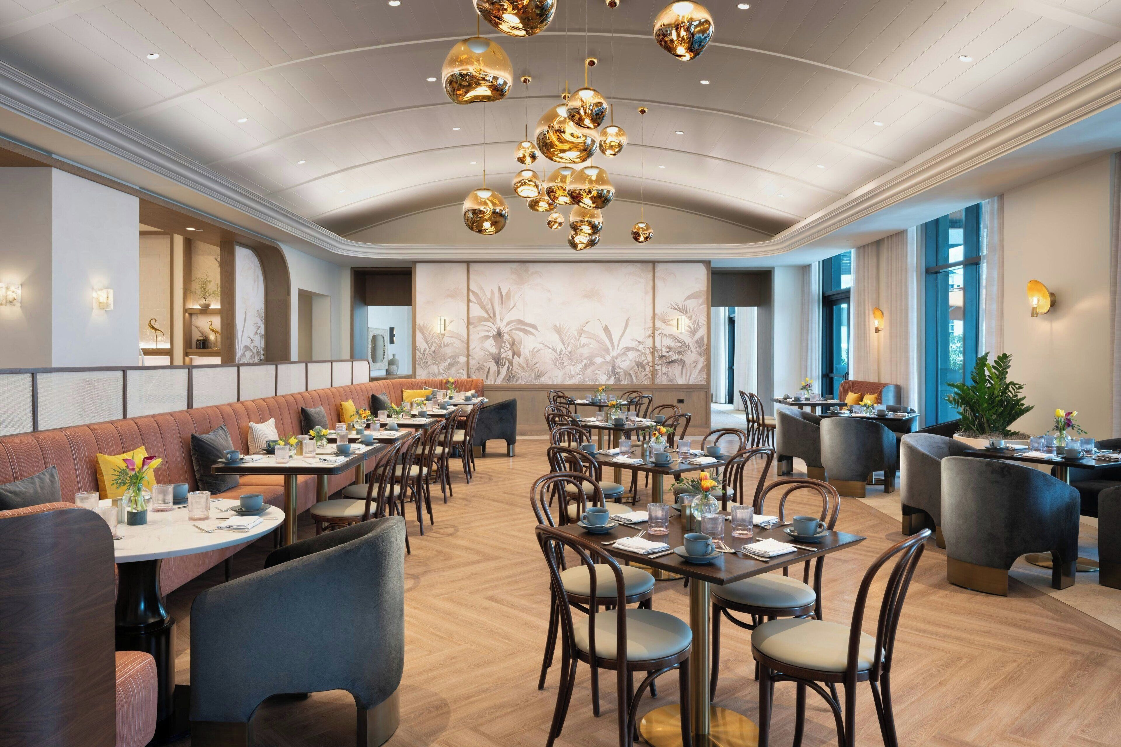 Ein geräumiges Restaurant mit hohen Decken, stilvollen Kronleuchtern und verschiedenen Sitzgelegenheiten, darunter Boxsitzgruppen und Tische.