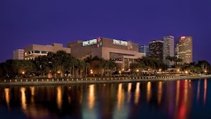 Un edificio moderno con el rótulo "STRAZ CENTER FOR THE PERFORMING ARTS" y un reflejo en el agua.