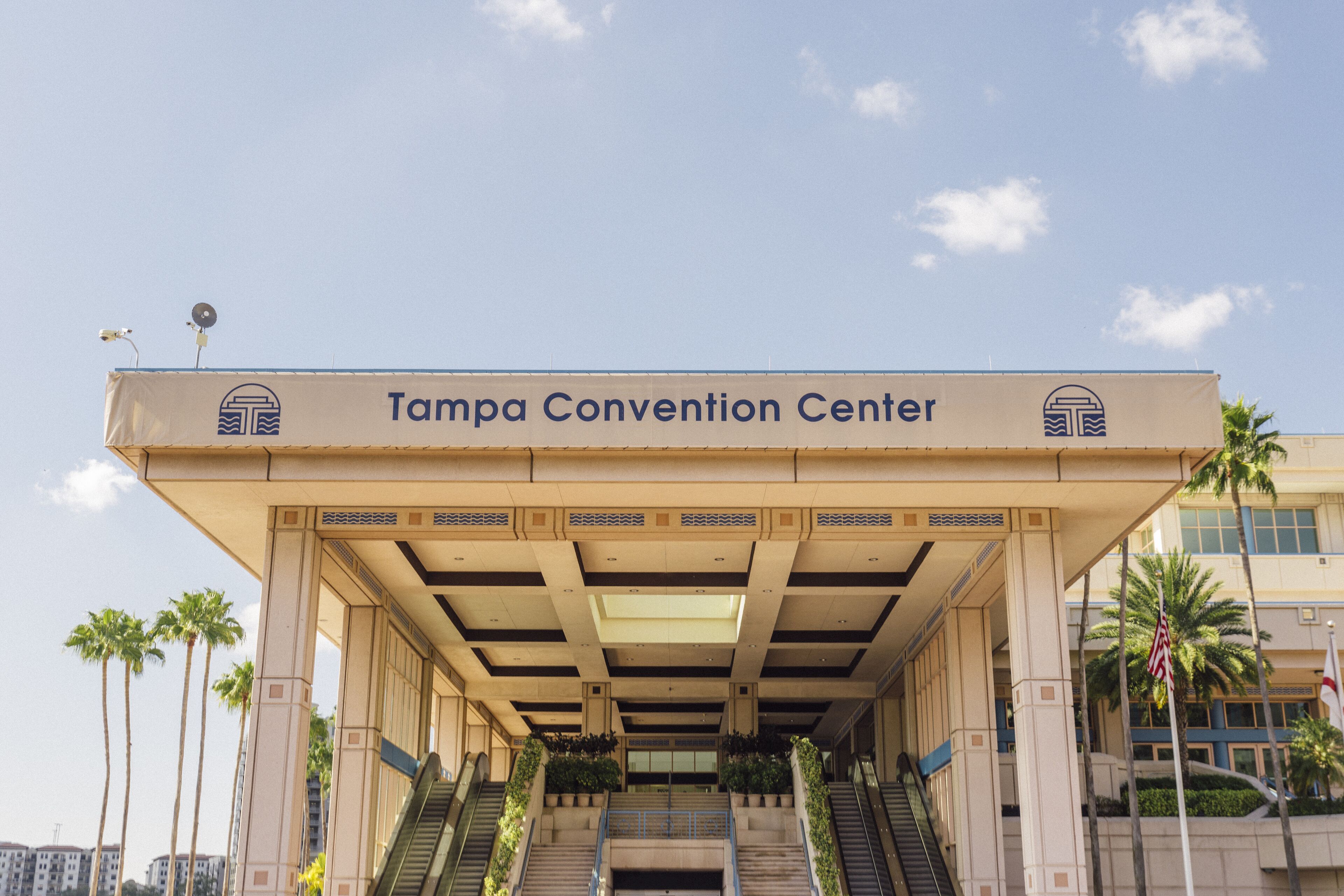 Entrada al Centro de Convenciones de Tampa con una galería techada, palmeras y cielo despejado.