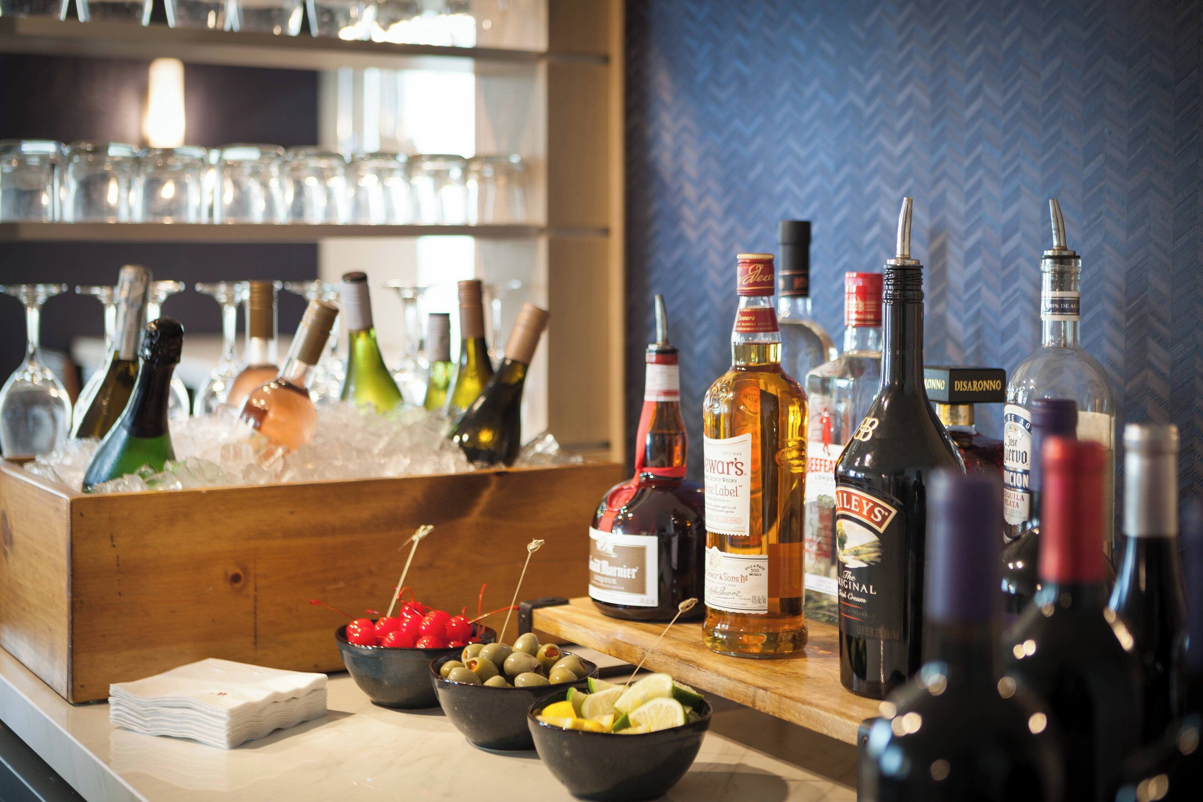 A bar area with various bottles of alcohol, glasses, and a wooden counter.