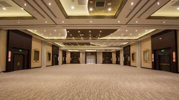 A large, carpeted room with multiple doors, recessed lighting, and decorative ceiling elements.