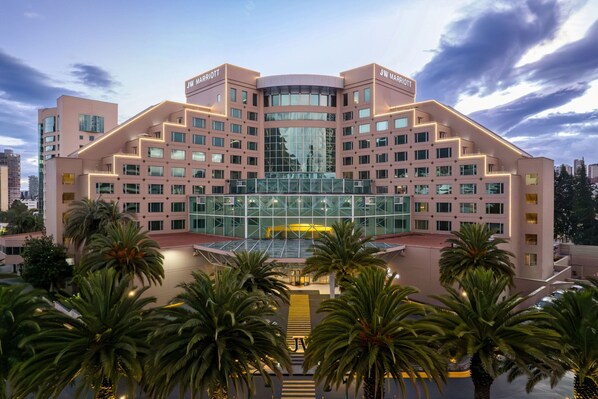 Un hotel JW Marriott con un diseño arquitectónico moderno, que destaca por una fachada de vidrio prominente y una distribución simétrica.