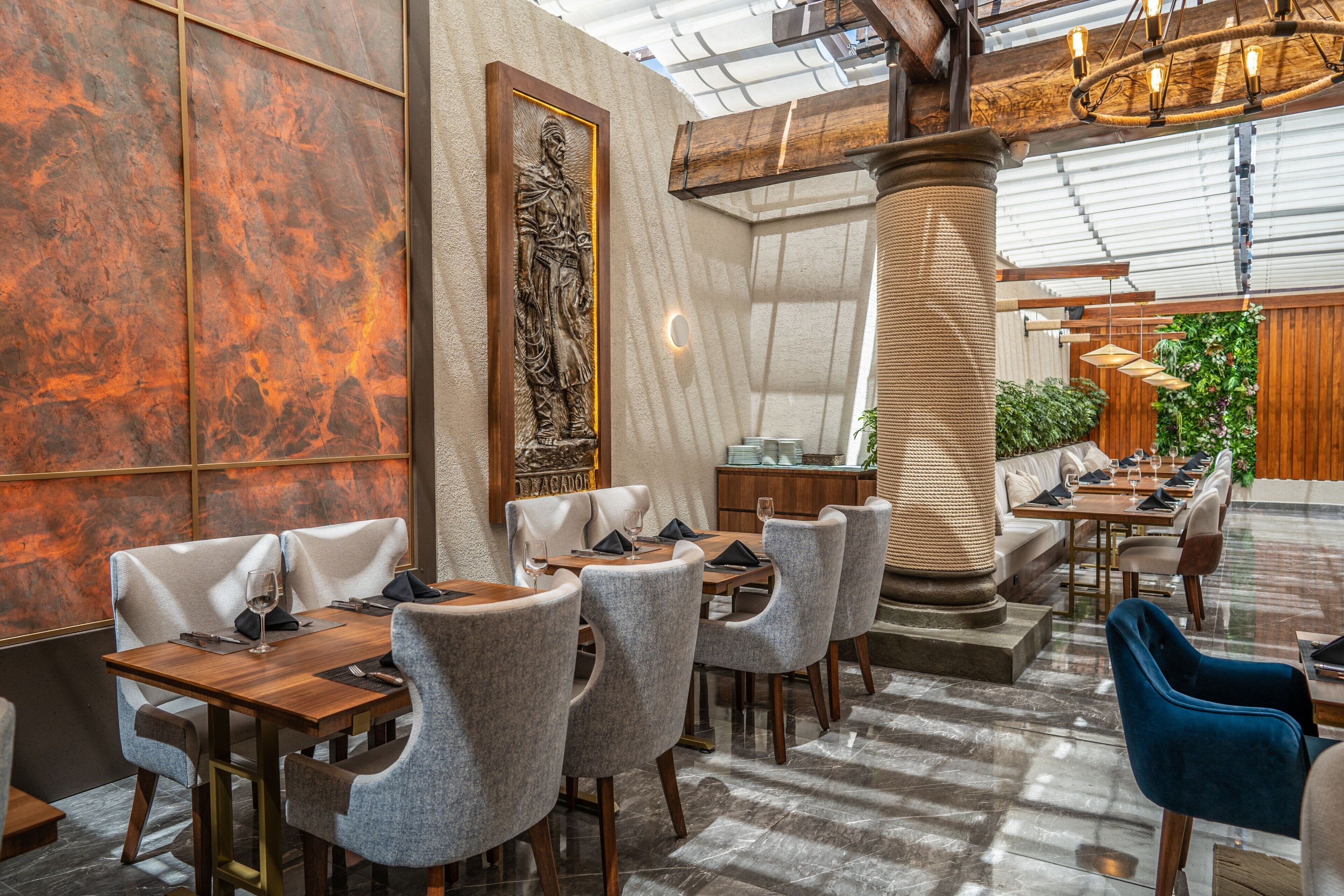 A restaurant with marble walls, a large column, and a high ceiling with exposed beams.