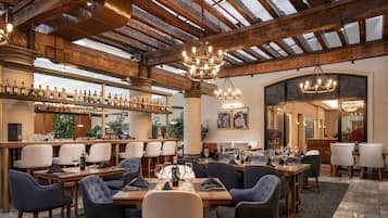 Un restaurante espacioso con techos altos, vigas a la vista y una zona de bar con gran variedad de botellas.