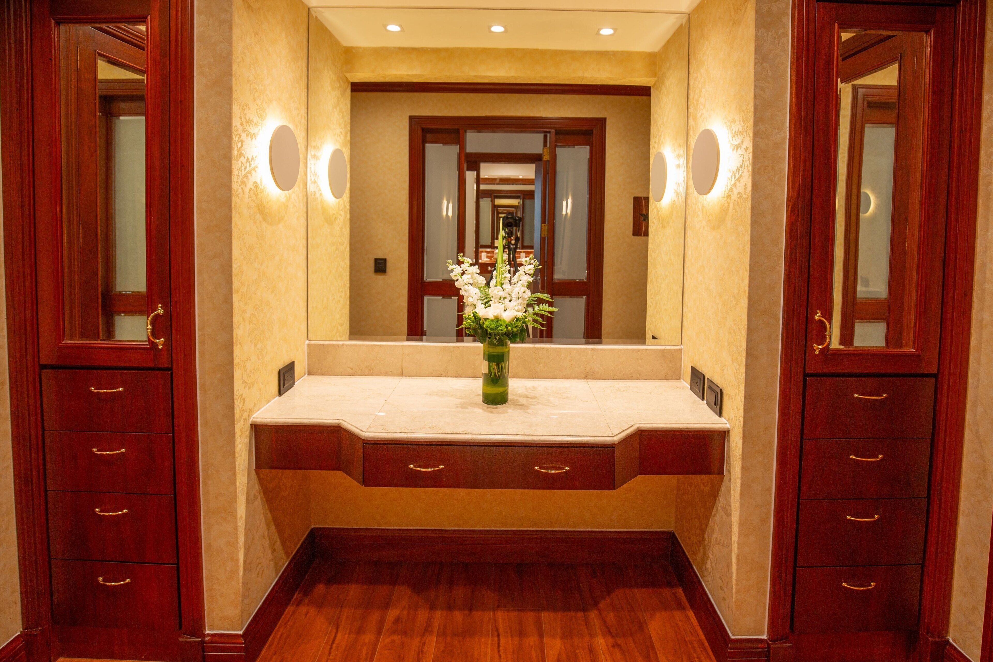Un couloir avec une coiffeuse, un miroir et des armoires en bois.
