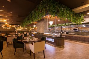 Un restaurante con una isla central, zona de estar y plantas colgantes.