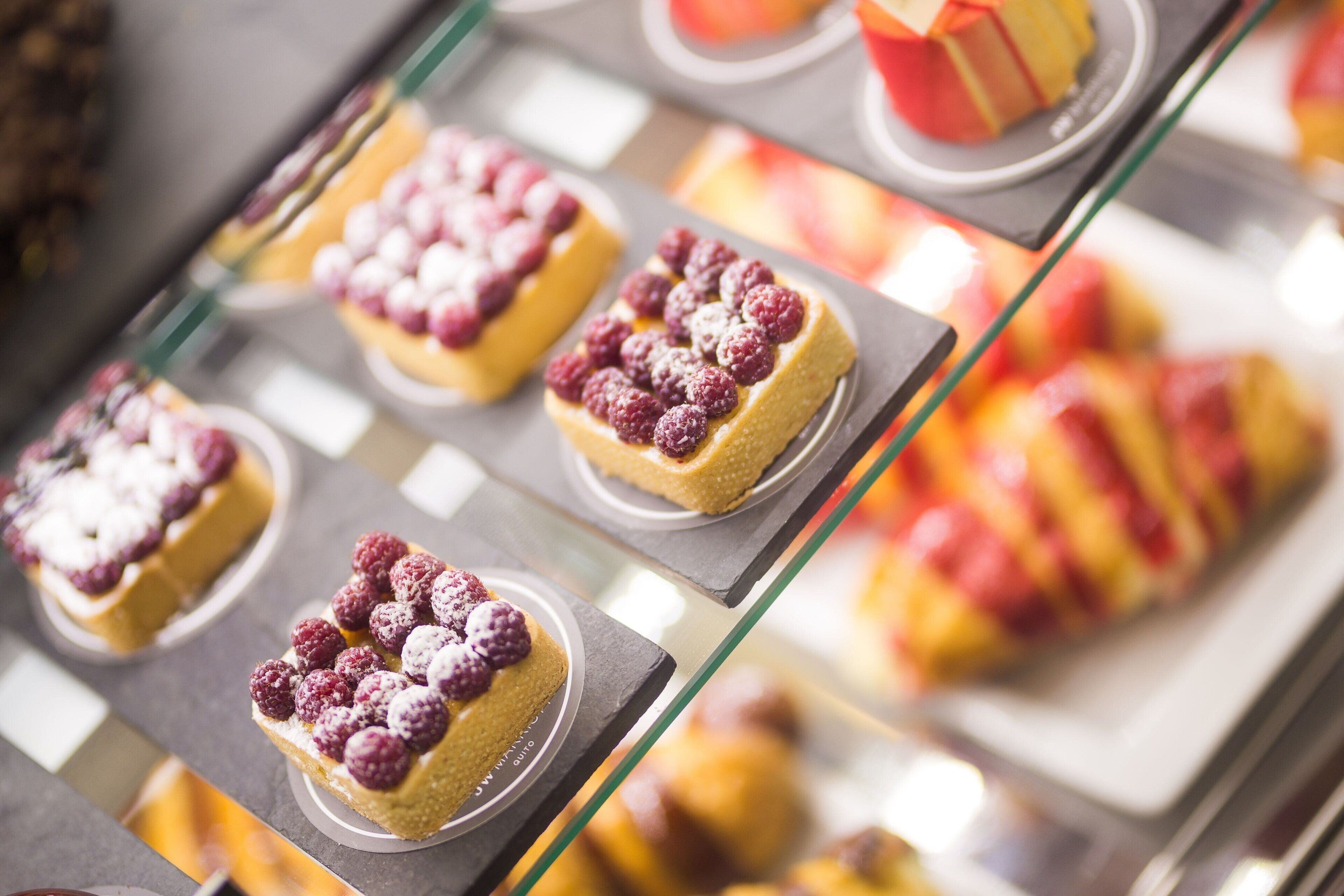 Una vitrina amb diversos pastissos, incloent postres cobertes amb raspberries.