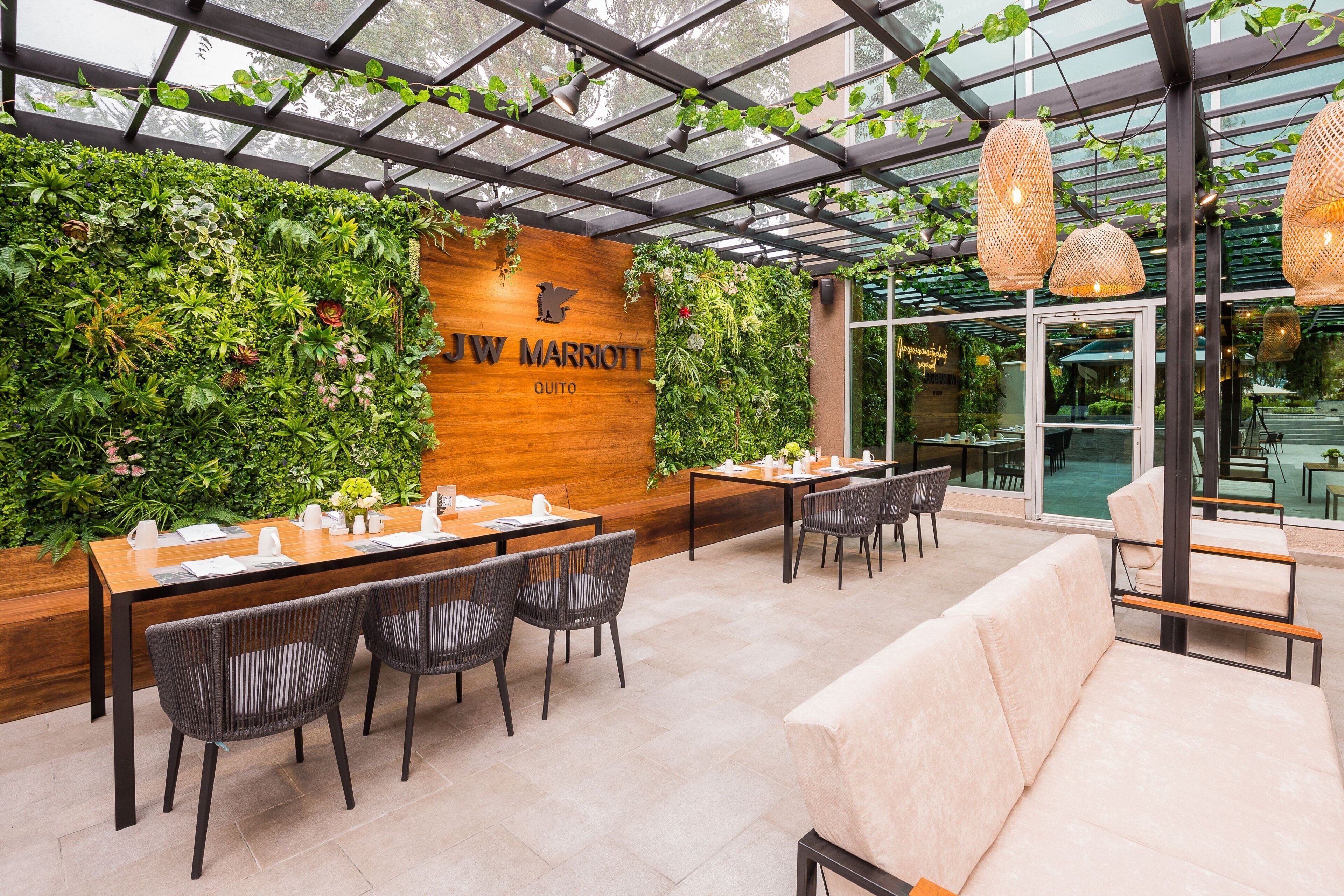Un restaurant de la chaîne JW Marriott doté d’un mur en bois, d’un jardin intérieur et de mobilier moderne.