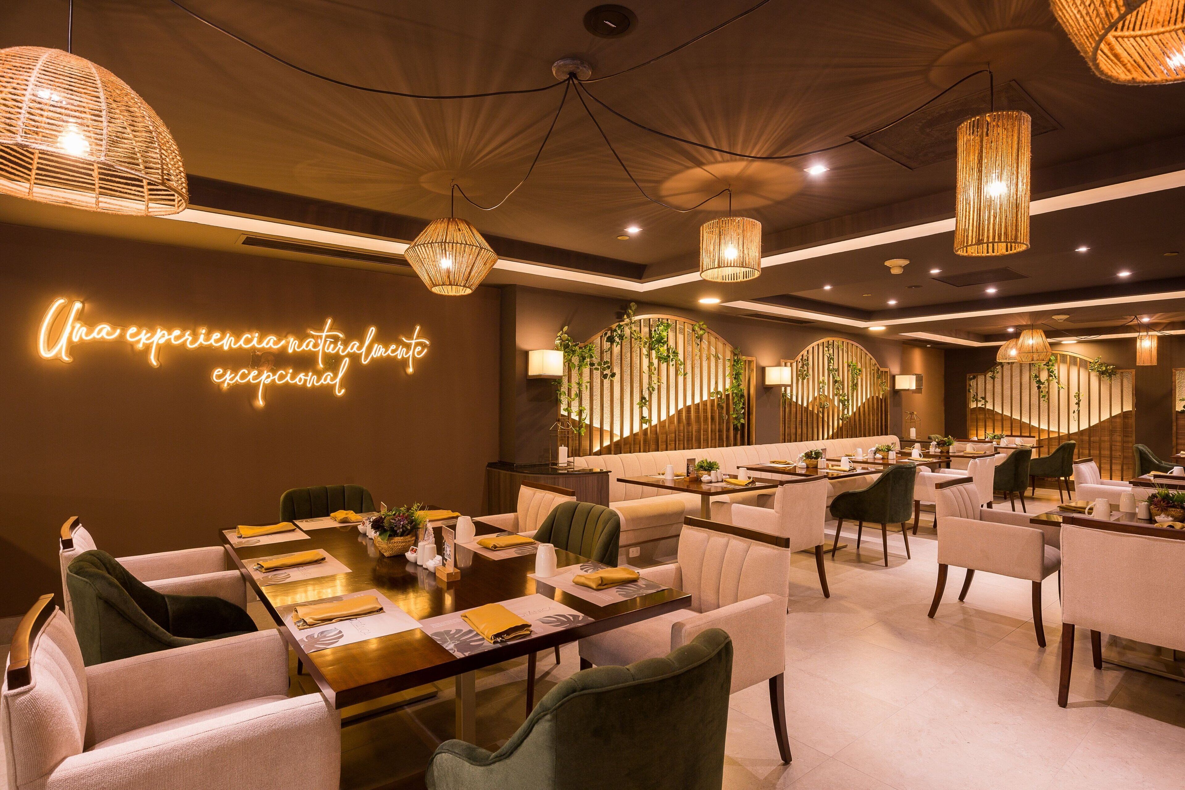 A modern dining area with a long table set for a meal, surrounded by comfortable seating.