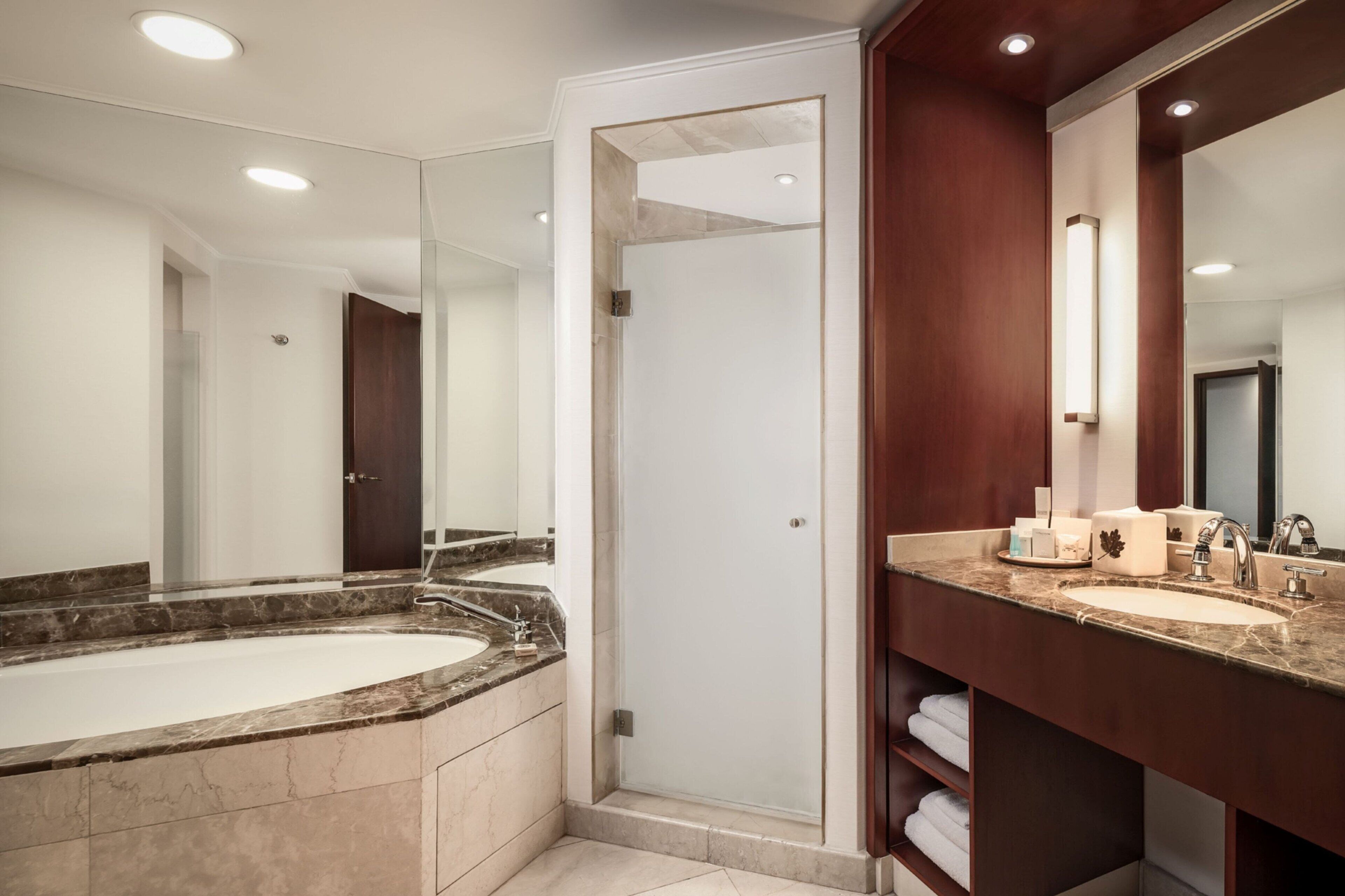 Une salle de bain moderne dotée d’une grande baignoire, d’une douche séparée et d’un meuble-lavabo avec un miroir.