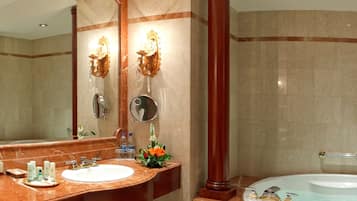 A bathroom with a marble sink, a large mirror, a wooden column, and a bathtub.