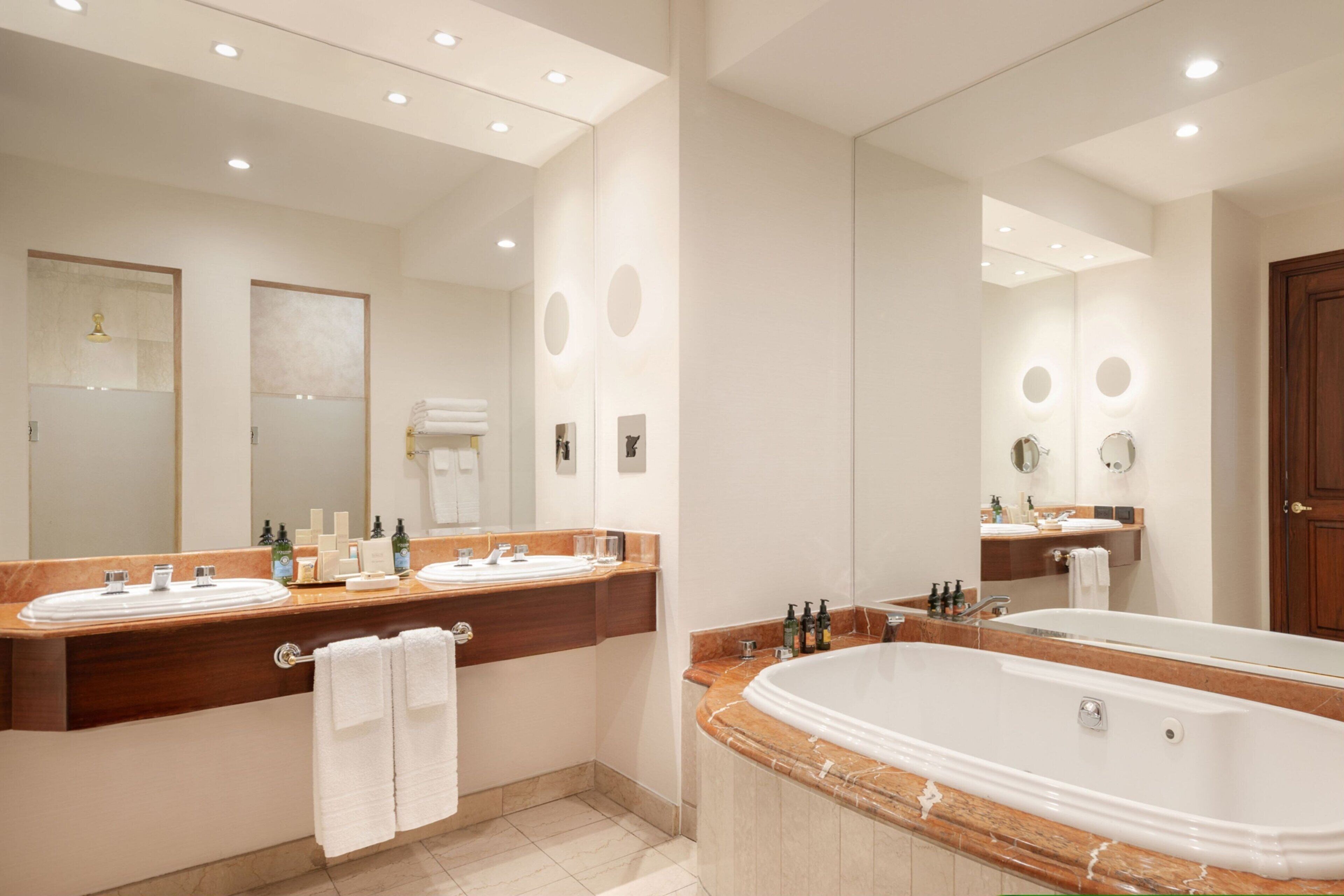 A modern bathroom with two sinks, a large bathtub, and a mirror.