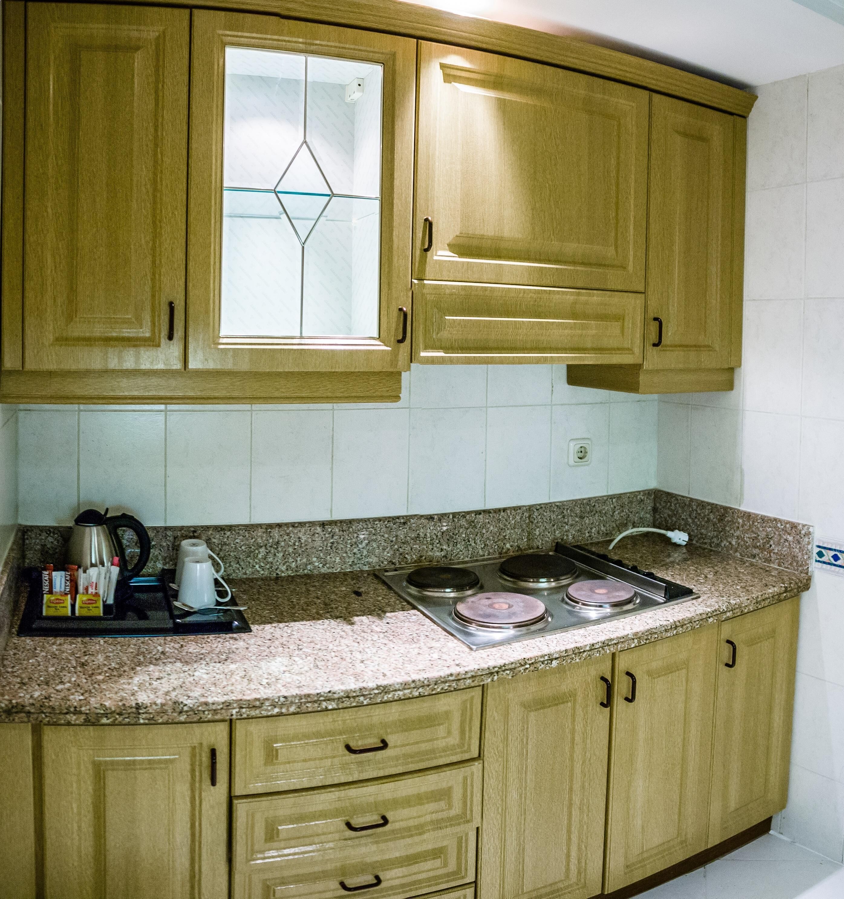A kitchen with wooden cabinets, a granite countertop, a stove, and a coffee maker.