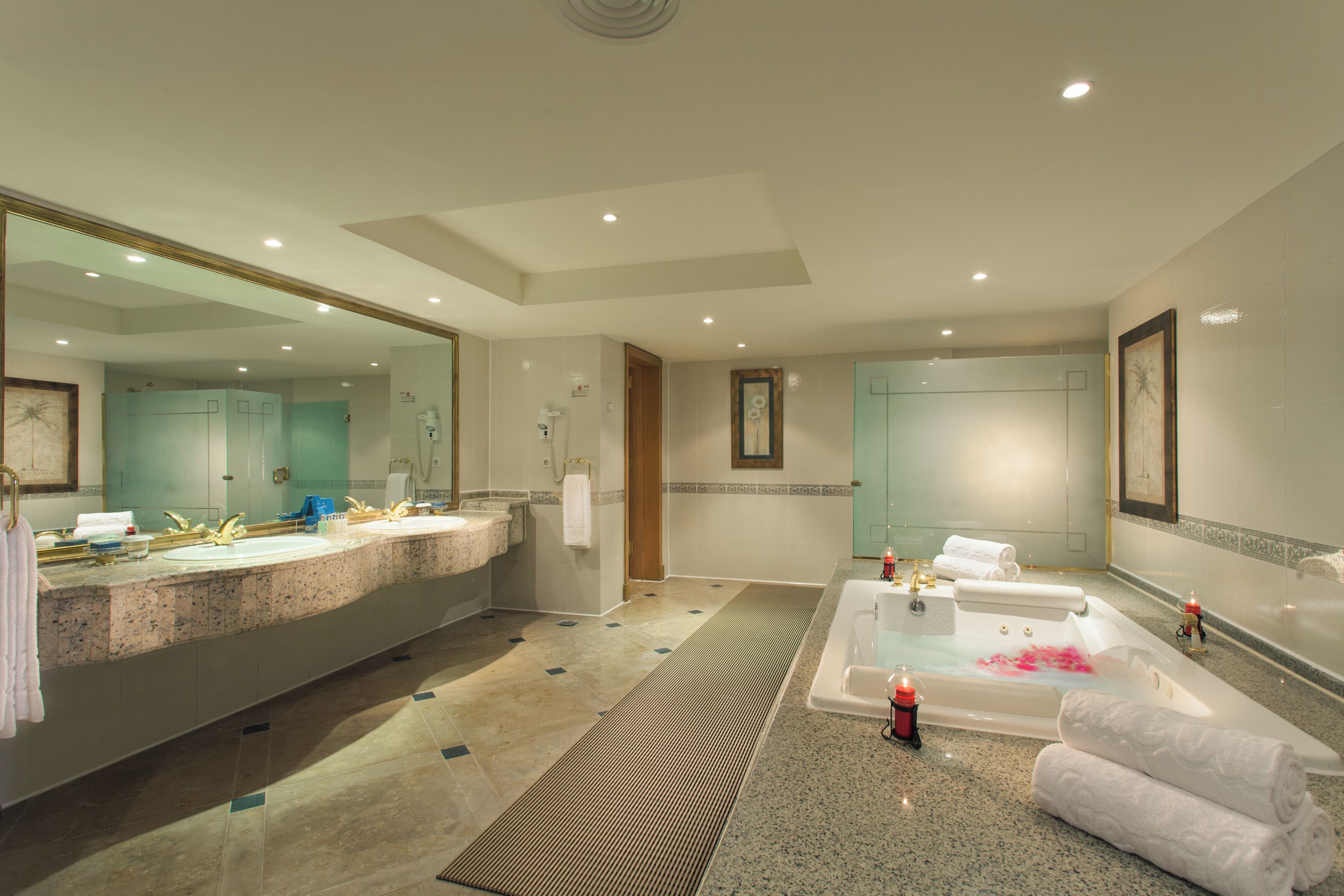 A spacious bathroom with a large sink, a bathtub with rose petals, and a mirror.