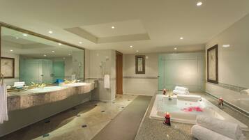A spacious bathroom with a large sink, a bathtub with rose petals, and a mirror.