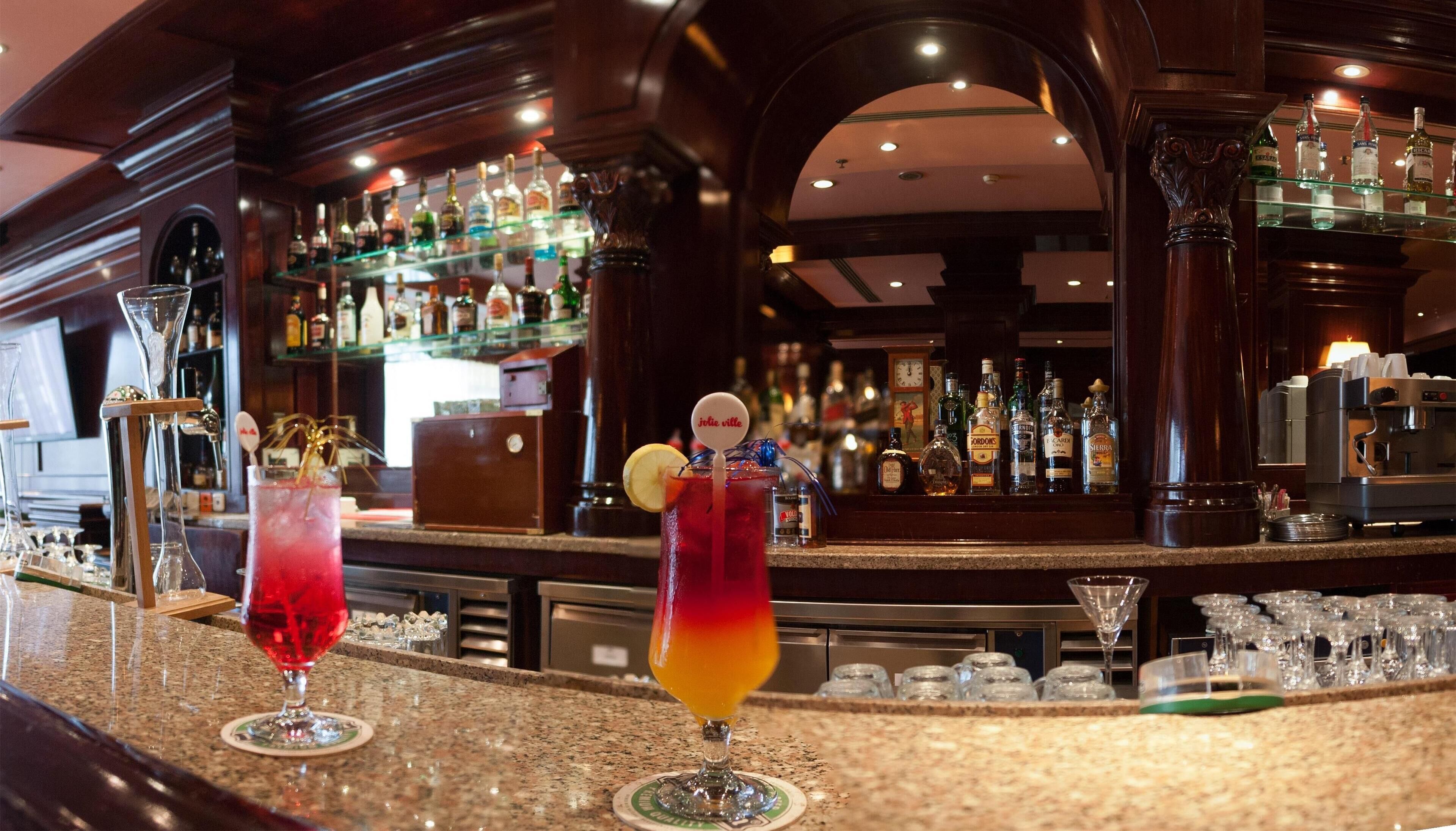 A bar area with a variety of liquor bottles and a coffee machine.