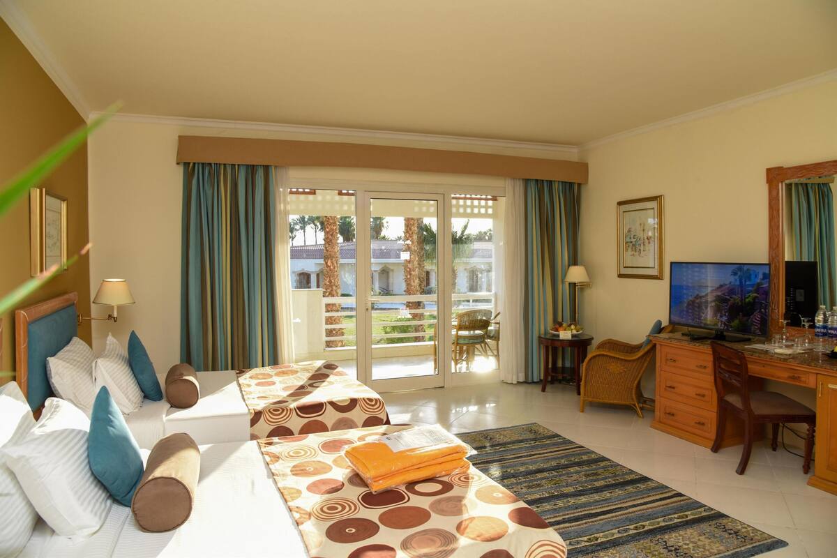 A hotel room with a bed, desk, and a view of the outdoors.