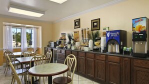 A breakfast area with a buffet setup, including a juice dispenser and a Maxwell House coffee maker. There are tables and chairs arranged for dining. - Microtel Inn & Suites by Wyndham Baton Rouge (Baton Rouge)