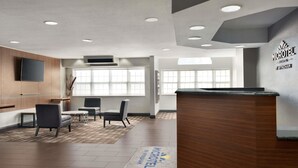 A modern reception area with a wooden reception desk, seating area with chairs, and large windows providing natural light. - Microtel Inn & Suites by Wyndham Baton Rouge (Baton Rouge)