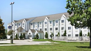 A multi-story hotel with a central entrance, a covered waiting area, and a well-maintained lawn. - Microtel Inn & Suites by Wyndham Baton Rouge (Baton Rouge)
