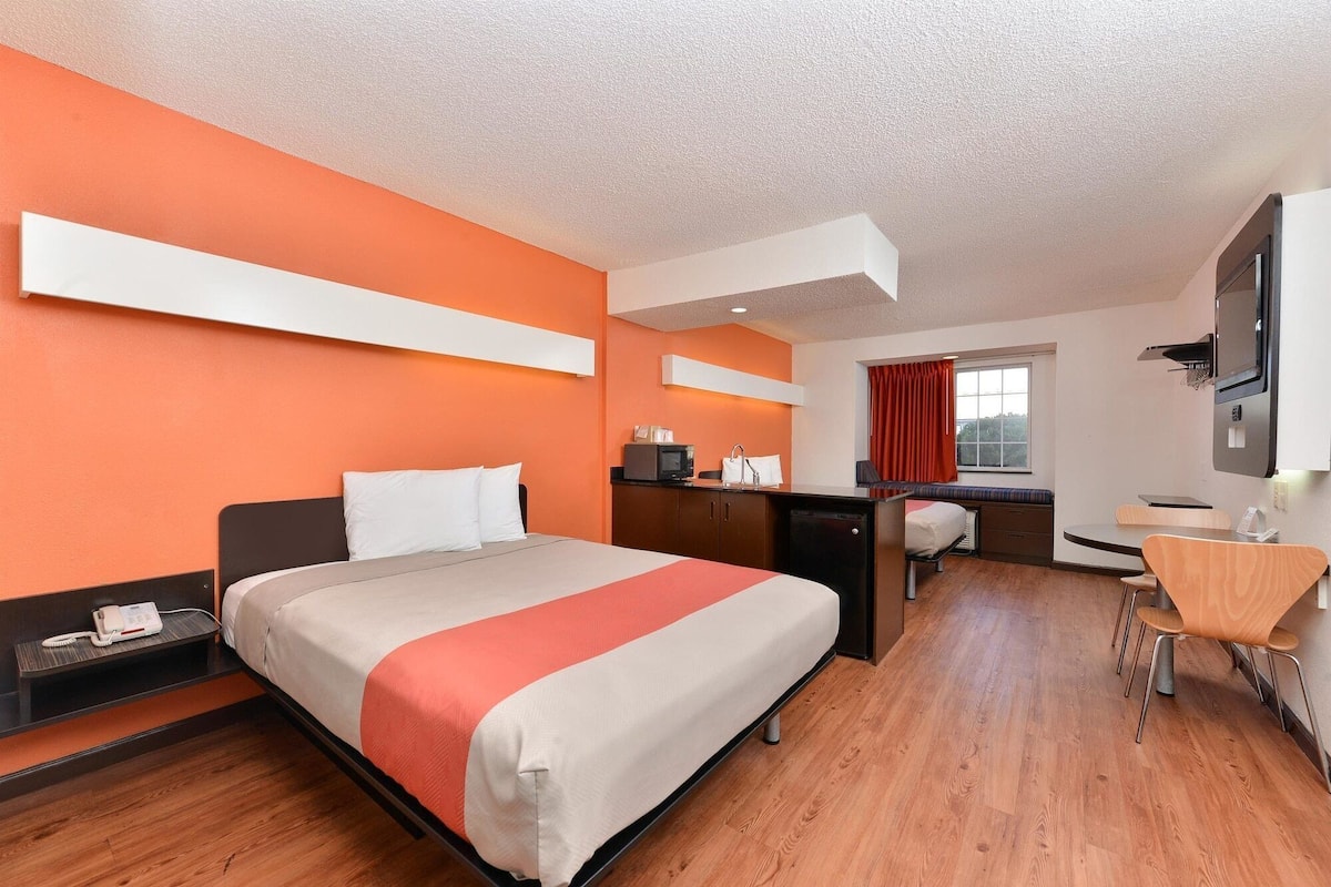 Een hotelkamer met een bed, bureau en badkamer.