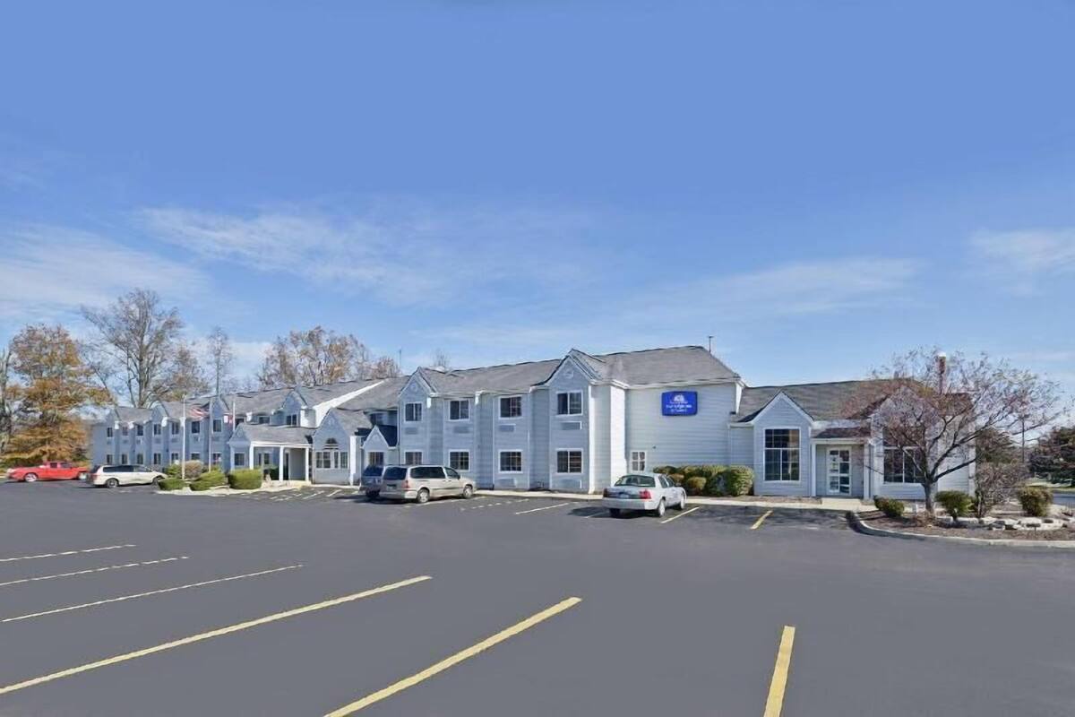 Un hotel con estacionamiento, varias construcciones y cielo despejado.