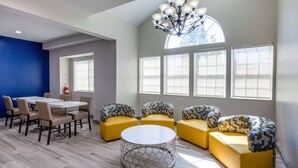 A modern lounge area with a round coffee table, yellow sofas, and a dining table with chairs. - Microtel Inn & Suites by Wyndham Sunbury/Columbus North (Sunbury)