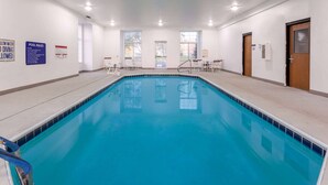 A large indoor swimming pool with clear pool rules signs, a diving board, and a view of the outside through large windows. - Microtel Inn & Suites by Wyndham Sunbury/Columbus North (Sunbury)