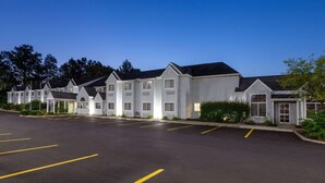 A row of white motel buildings with a parking lot in front. - Microtel Inn & Suites by Wyndham Sunbury/Columbus North (Sunbury)