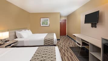 Una habitación de hotel con dos camas, un escritorio, una silla, un televisor y una puerta.